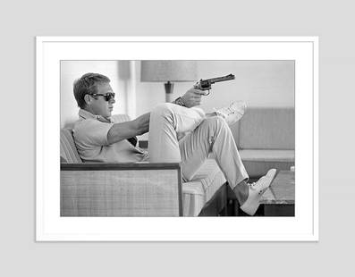 Steve Mcqueen Takes Aim With Gun Framed In White: Description At his bungalow in Palm Springs, Steve McQueen practices his aim before heading out for a shooting session in the desert. Photo by John Dominis 1963 archival pigment print framed in white