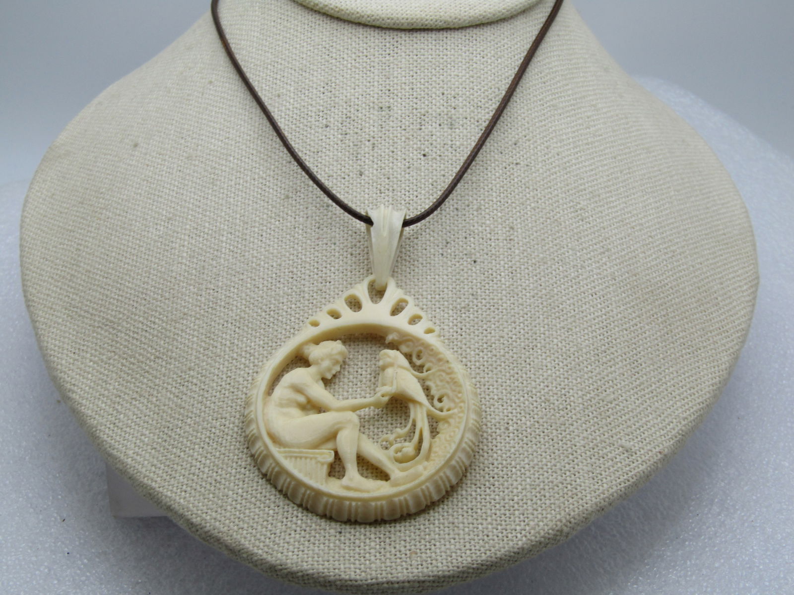 Vintage Carved Bone Woman & Parrot Pendant/Necklace, 18"-20": Vintage Carved Bone Woman & Parrot Pendant/Necklace, 18"-20". The looks is of a Roman or Grecian woman sitting on a carved bench paying attention to a parrot with a long curled tail. The necklace is a