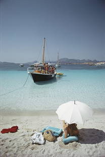Waiting In The Shade ' By Slim Aarons Oversized C Type: Description ' Waiting In The Shade ' by Slim Aarons A woman shelters under a parasol on a beach on the Costa Smeralda, Sardinia, 1967. (Photo by Slim Aarons/Hulton Archive/Getty Images) Paper size 16