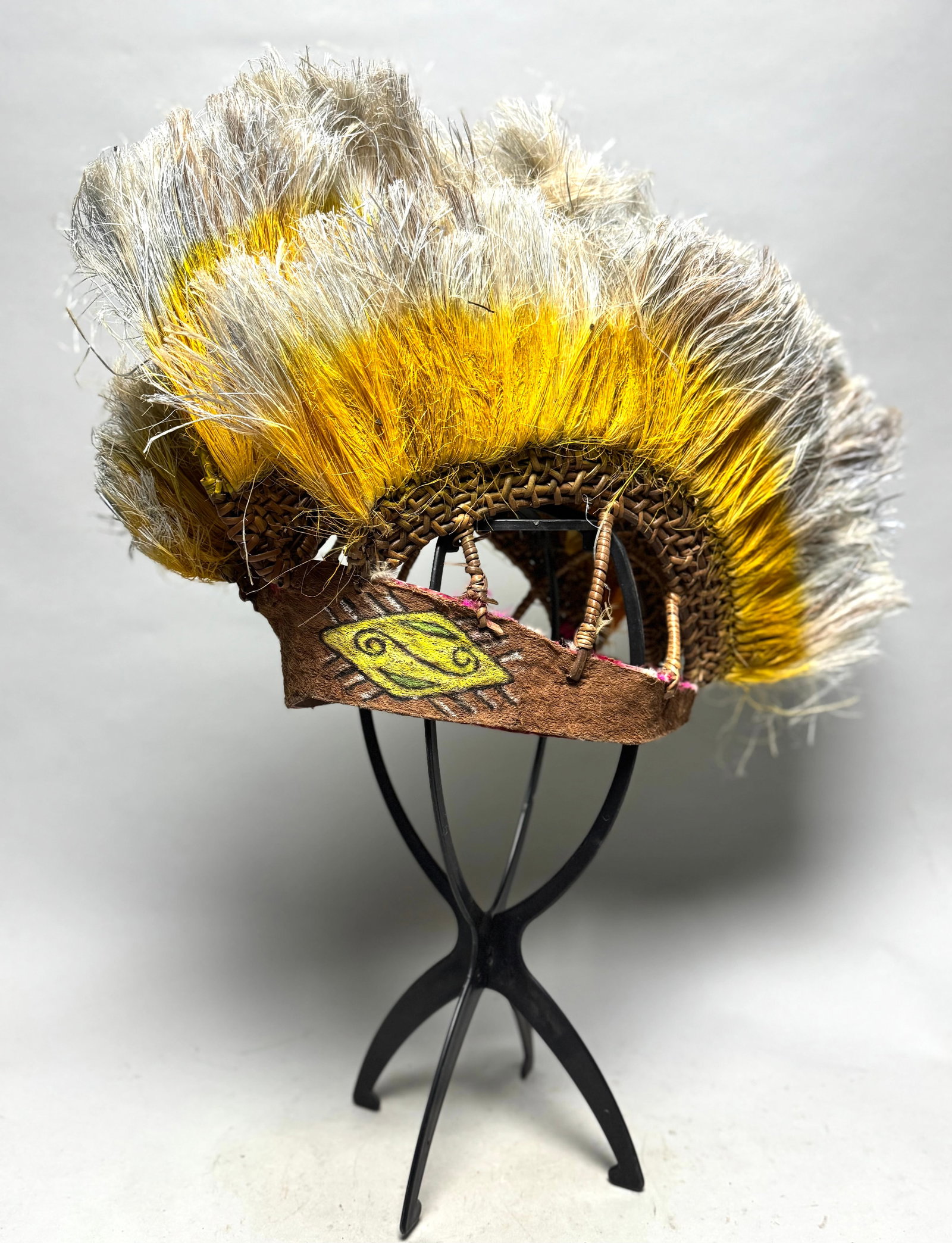 Headdress Lake Sentani - West Papua: This largest cap is especially notable: it features yellow and white plant fibers that are cleverly arranged to evoke the plumage of the bird of paradise?a subtle and intelligent tribute to one of Pap