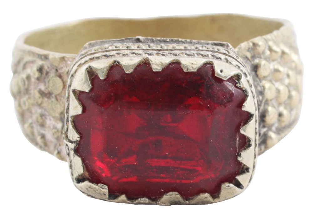EASTERN EUROPEAN GYPSY RING, 19TH CENTURY, SIZE 8 ¾: 19th century. White metal band 4.7mm width flaring to the foliate and pellet decorated shoulders. Large rectangular bezel with cabled bottom and saw tooth edge and faceted red “stone”. Att