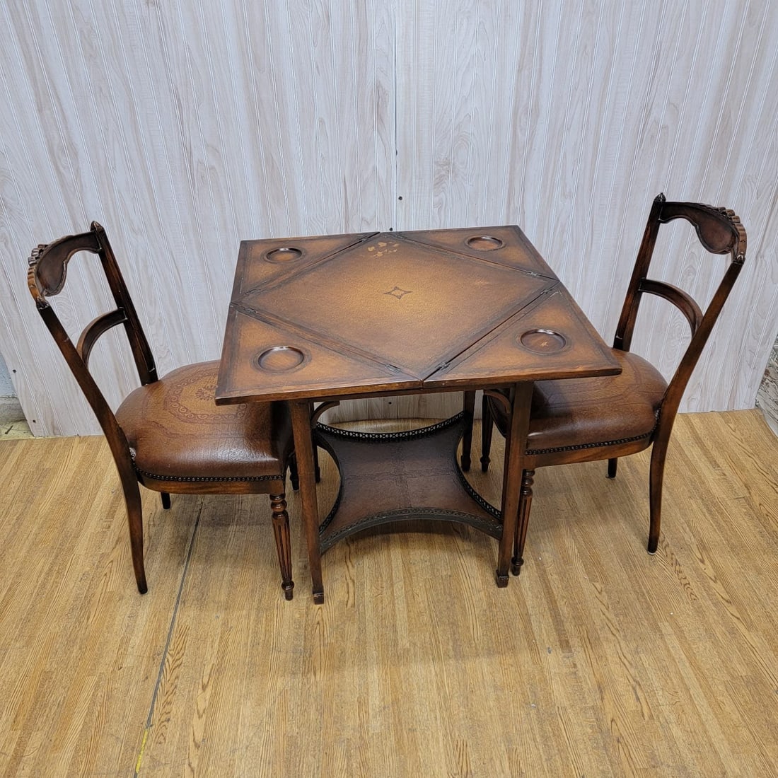 Antique Carved Mahogany and Tooled Leather Napkin Folding Table and 2 Chairs: Vintage from before 2000 Materials: wood, leather, mahogany Antique Carved Mahogany and Tooled Leather Napkin Folding Table and 2 Matching Chairs - 3 Pieces This set would be perfect as a small dining