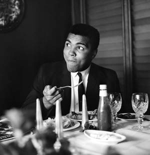 Muhammad Ali ' By Terry Fincher Oversized Resin: Description ' Muhammad Ali ' by Terry Fincher 16th August 1965: World heavyweight boxing champion Muhammad Ali enjoys supper in a restaurant. (Photo by Terry Fincher/Express/Getty Images) Paper size 2