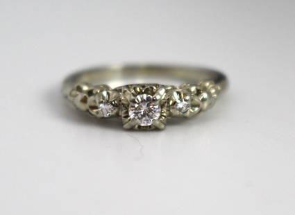 Diamond Three-Stone Ring in 18ct White Gold: Diamond Three-Stone Ring in 18ct White Gold This elegant three-stone diamond ring features a central round brilliant cut diamond, accompanied by two smaller round diamonds on either side. The central