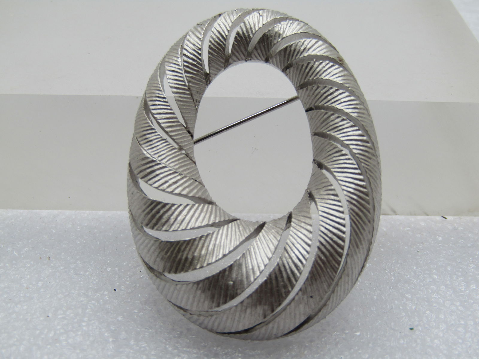 Vintage Crown Trifari Oval Brooch, 1960's-1970's Open Work: Vintage Crown Trifari Oval Brooch, 1960's-1970's Open Work, satiny textured silver tone finish. Tapered thickness from 11mm and appx. 17.5mm at the bottom. Signed Crown Trifari on the back. (W12024.2