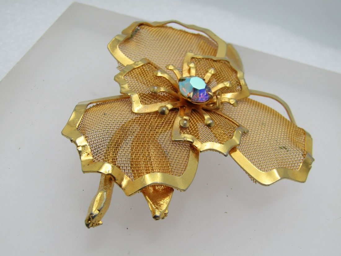 Vintage Mesh Floral Brooch, AB Rhinestone, 1960's-1970's: Vintage Mesh Floral Brooch, AB Rhinestone, 1960's-1970's. It is 3.25" by 2.5" with a center 8mm aurora borealis rhinestone. In the phone the one anther sticking out around the stone is bent inward, th