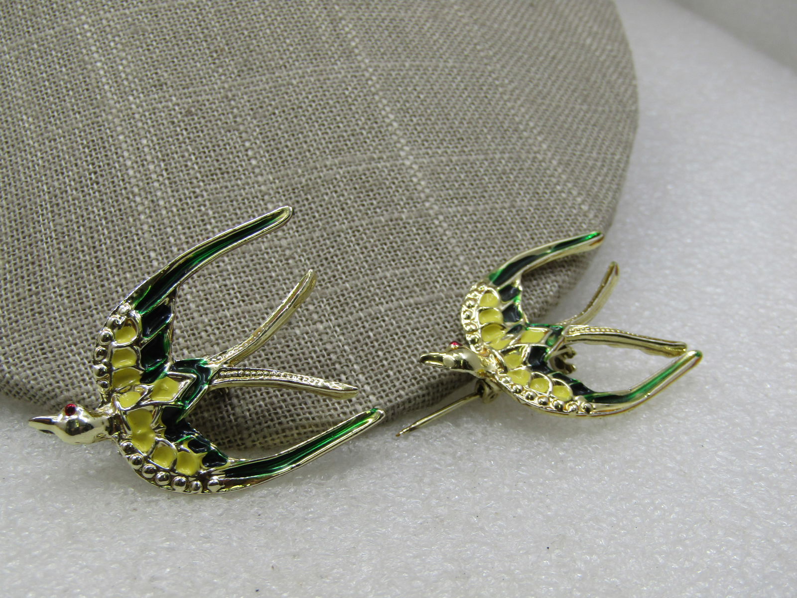 Vintage Pair Enameled Swallow Bird Brooches, 1960's: Vintage Pair Enameled Swallow Bird Brooches, 1960's, 1.5" by 1.25" enameled in yellow and green on the wings and a red enameled eye. Scatter pin set. Gold tone. Not isgned by the maker. Very good cond