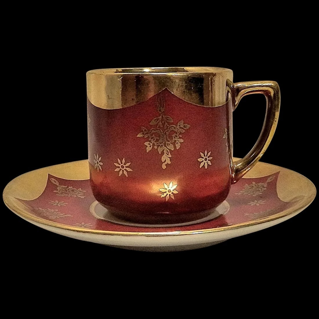 Vintage Bavarian Porcelain Demitasse Teacup & Saucer by Winterling in Garnet and Gold - Circa 1950s: Vintage Bavarian Porcelain Demitasse Tea Cup & Saucer by Winterling in Garnet and Gold - Circa 1950s is crafted of fine porcelain. The outside of the tea cup is glazed in a deep garnet color overlaid