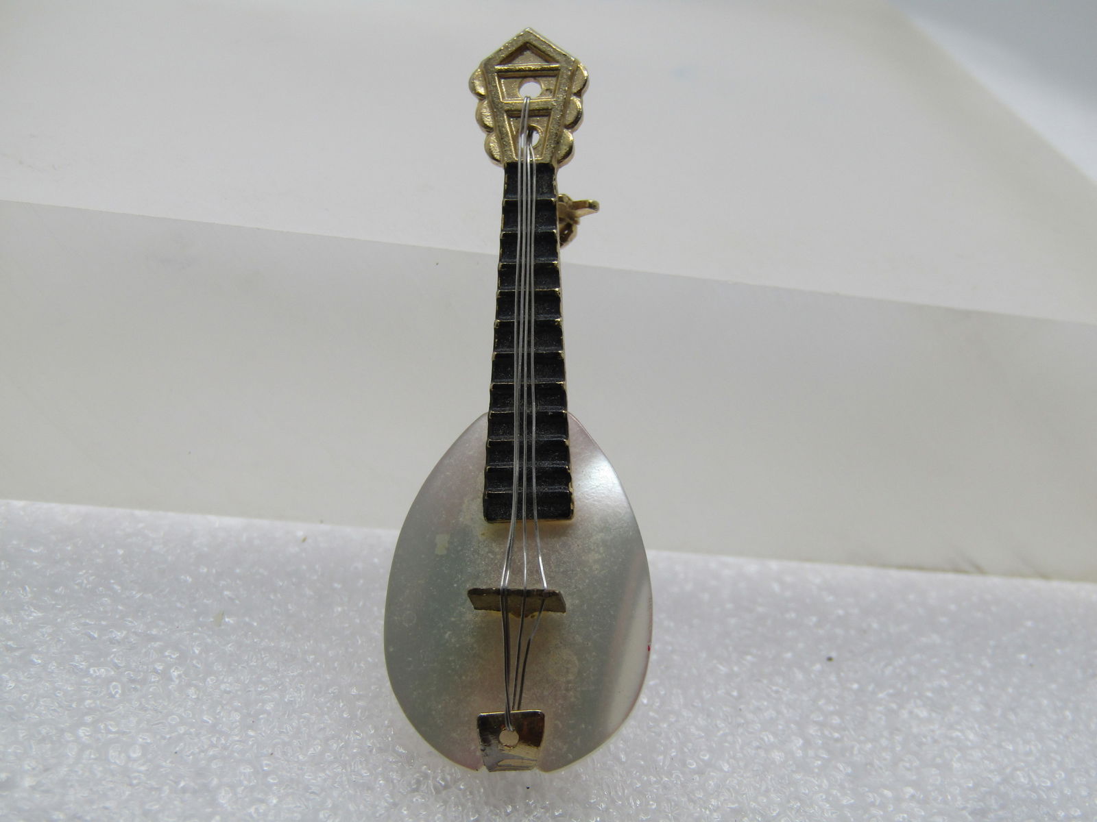 Vintage MOP Mandolin Brooch, 1960's-1970's: Vintage MOP Mandolin Brooch, 1960's-1970's. Gold tone top with black enameled neck and silver tone strings. It has a locking clasp. It is not signed or marked. It is appx. 2" tall and 3/4" wide at the