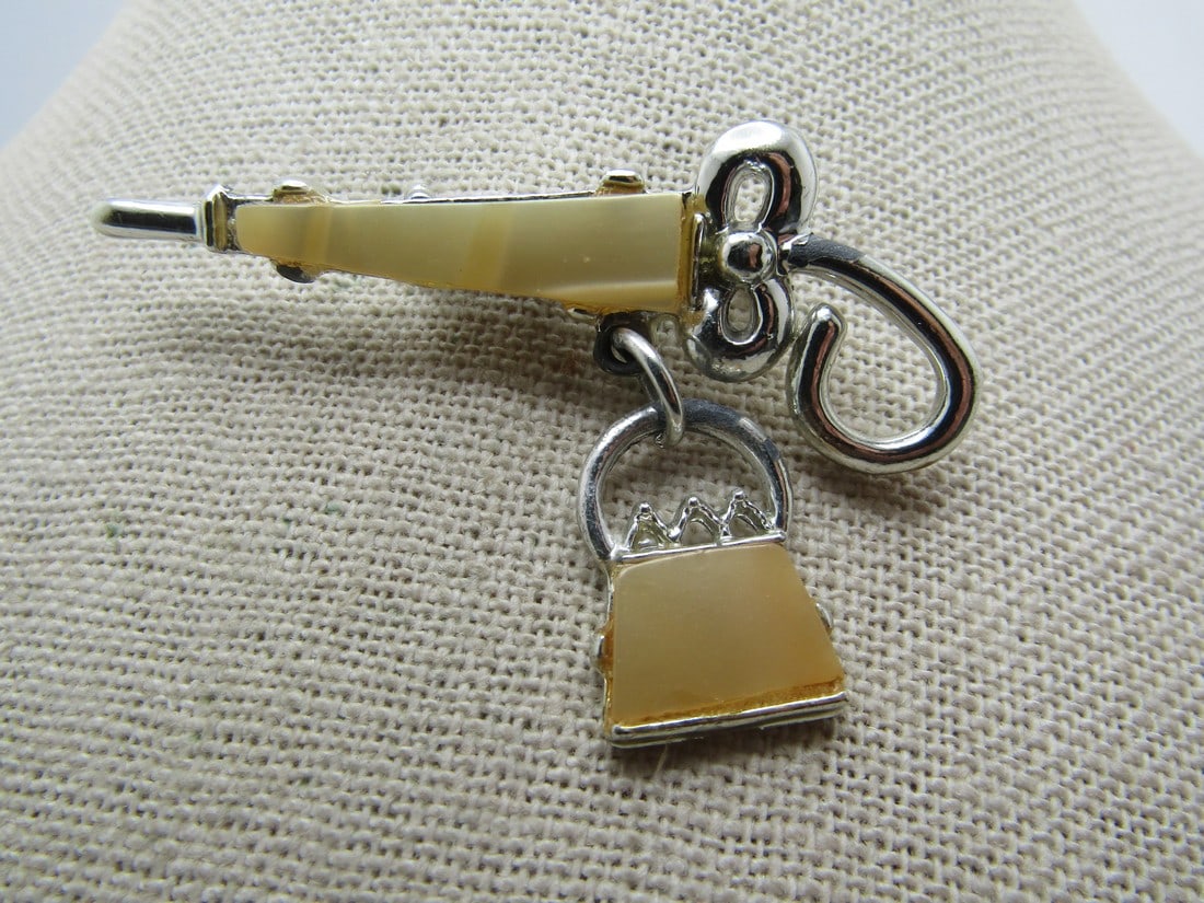 Vintage Faux MOP Umbrella & Purse Brooch, 1950's-1960's: Vintage Faux MOP Umbrella & Purse Brooch, 1950's-1960's. Silver tone and appx. 2.25" tall and 1" wide with a dangling purse. Curled handles. There is a piece of faux mother-of-pearl in both the umbrel