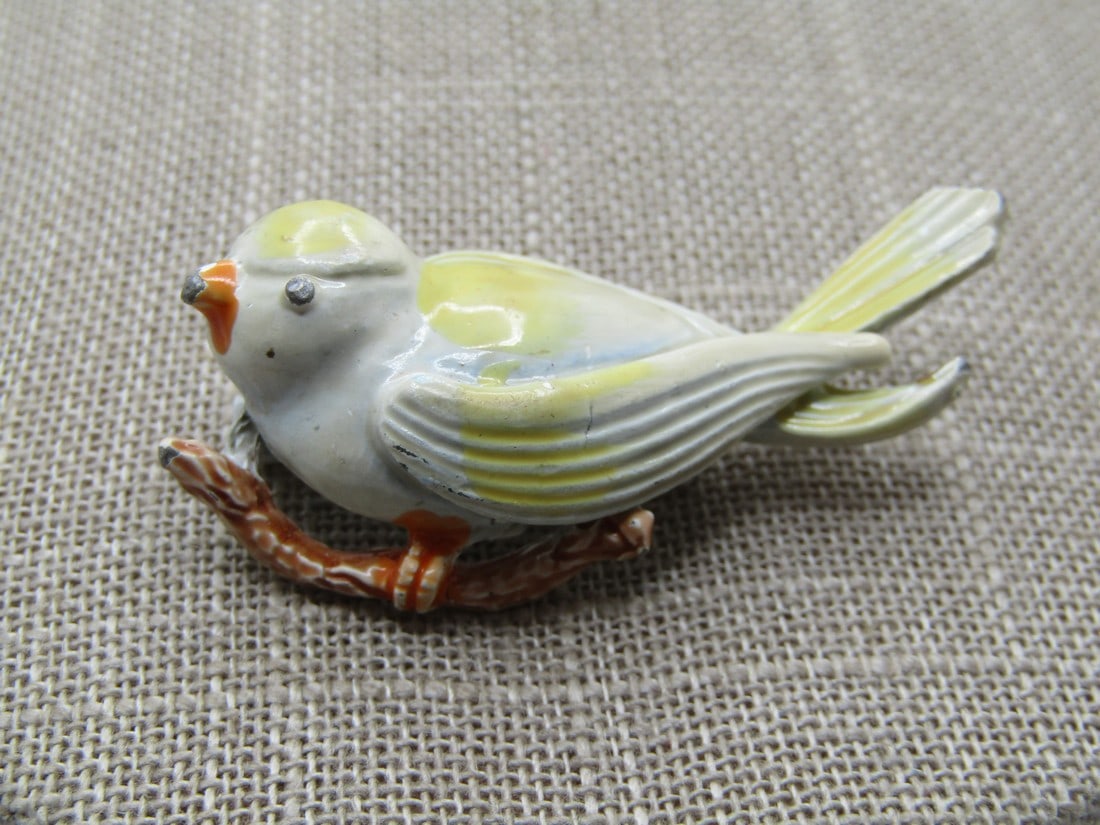 Vintage Enameled Bird on Branch Brooch, 1950's-1960's: Vintage Enameled Bird on Branch Brooch, 1950's-1960's. Yellow and white enameled bird with orange beak and feet on a brown branch. Lockign clasp and white enameled back. It is appx. 2" by .75" tall. I