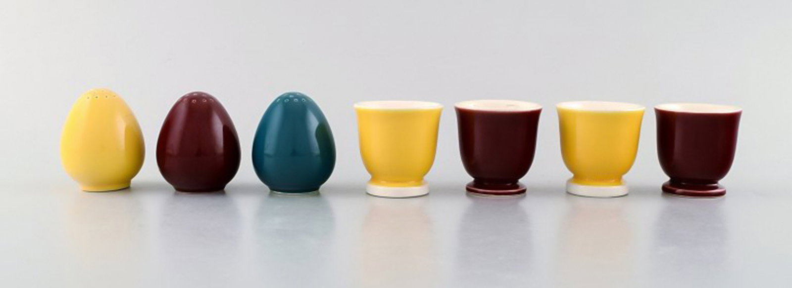 Confetti Royal Copenhagen / Aluminum faience. Three salt shakers and four egg cups in glazed: Confetti Royal Copenhagen / Aluminum faience. Three salt shakers and four egg cups in glazed faience. Bordeaux, yellow and turquoise glaze. The salt shaker measures: 5.5 x 5 cm. The egg cup measures:
