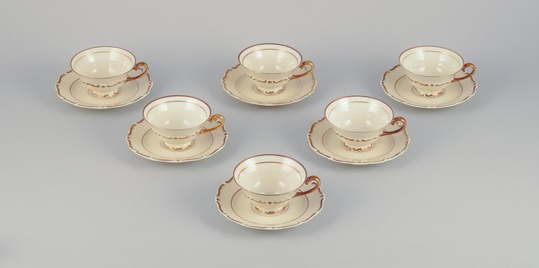 A set of six KP, Karlskrona tea cups with saucers in cream-colored porcelain with gold decoration.: A set of six KP, Karlskrona (Sweden) tea cups with saucers in cream-colored porcelain with gold decoration. Classic style. 1930s/1940s. Marked. In perfect condition. Cup: D 9.6 cm. without the handle