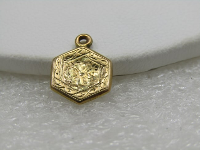 Vintage 12kt Gold Engraved Floral Charm/Pendant, Six Sided: Vintage 12kt Gold Engraved Floral Charm/Pendant, Six Sided. It is appx. 5/8" tall with spring ring and 1/2" wide. It has a flower in the center with engraved scrolls around it. It tests s 12kt gold at