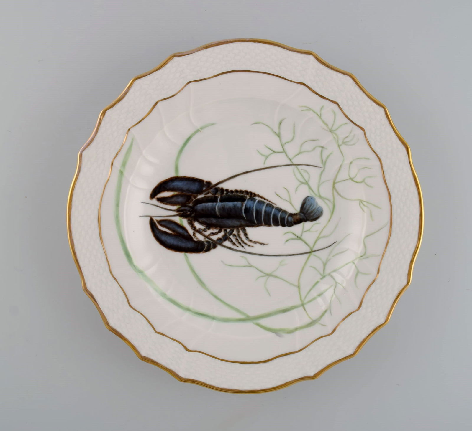 Royal Copenhagen porcelain dinner plate with hand-painted fish motif and golden border. Flora /: Royal Copenhagen porcelain dinner plate with hand-painted fish motif and golden border. Flora / Fauna Danica style. Dated 1957. Diameter: 25.5 cm. In excellent condition. Stamped. 3rd factory quality.