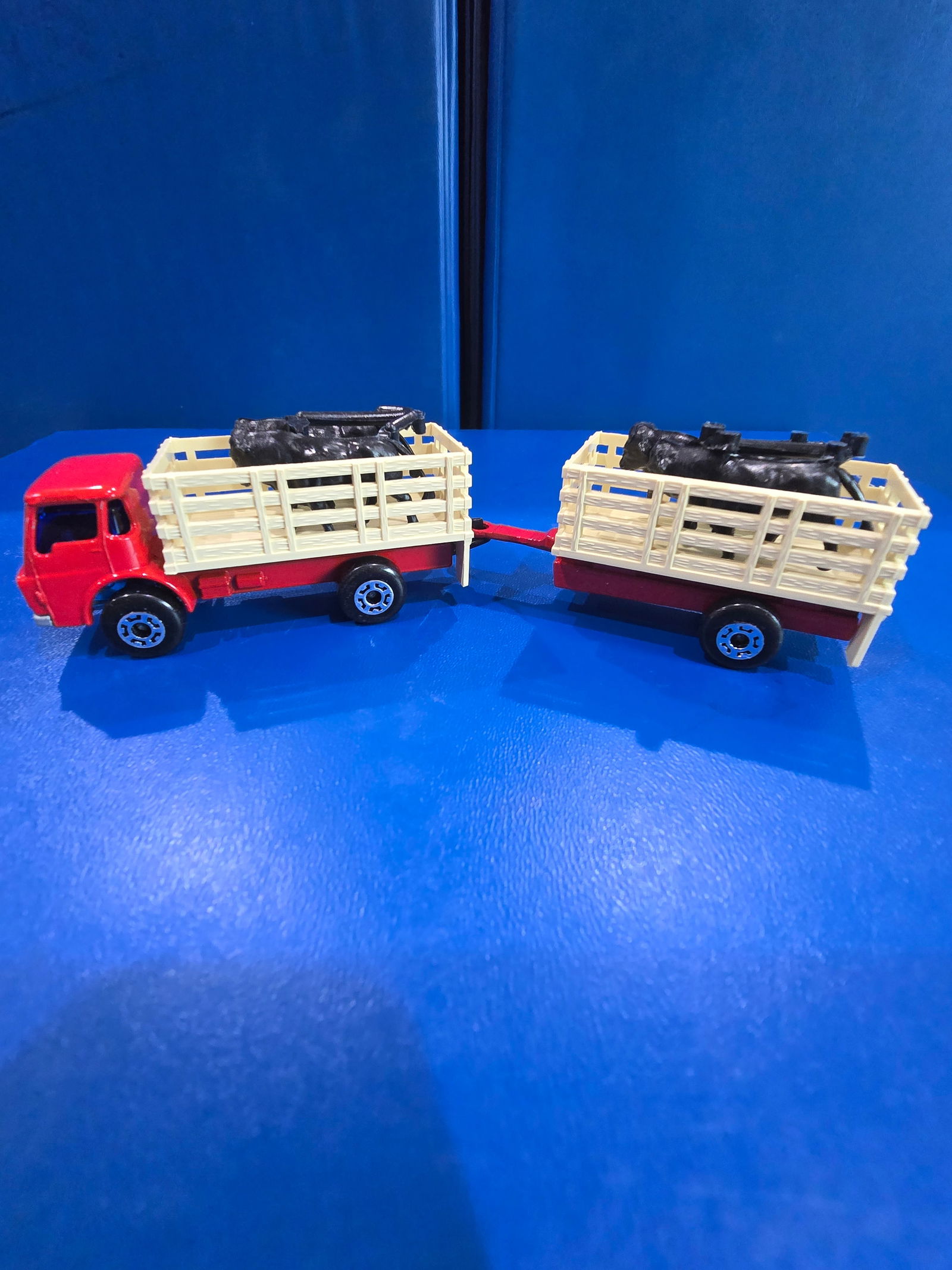 Red truck blue windows, silver painted base, Tan bed, black cows, red trailer, black base, tan bed,: Title: Matchbox Superfast Cattle TruckDescription: Red truck blue windows, silver painted base, Tan bed, black cows, red trailer, black base, tan bed, black cowsDate/Period: 1976Materials: metal Dimen