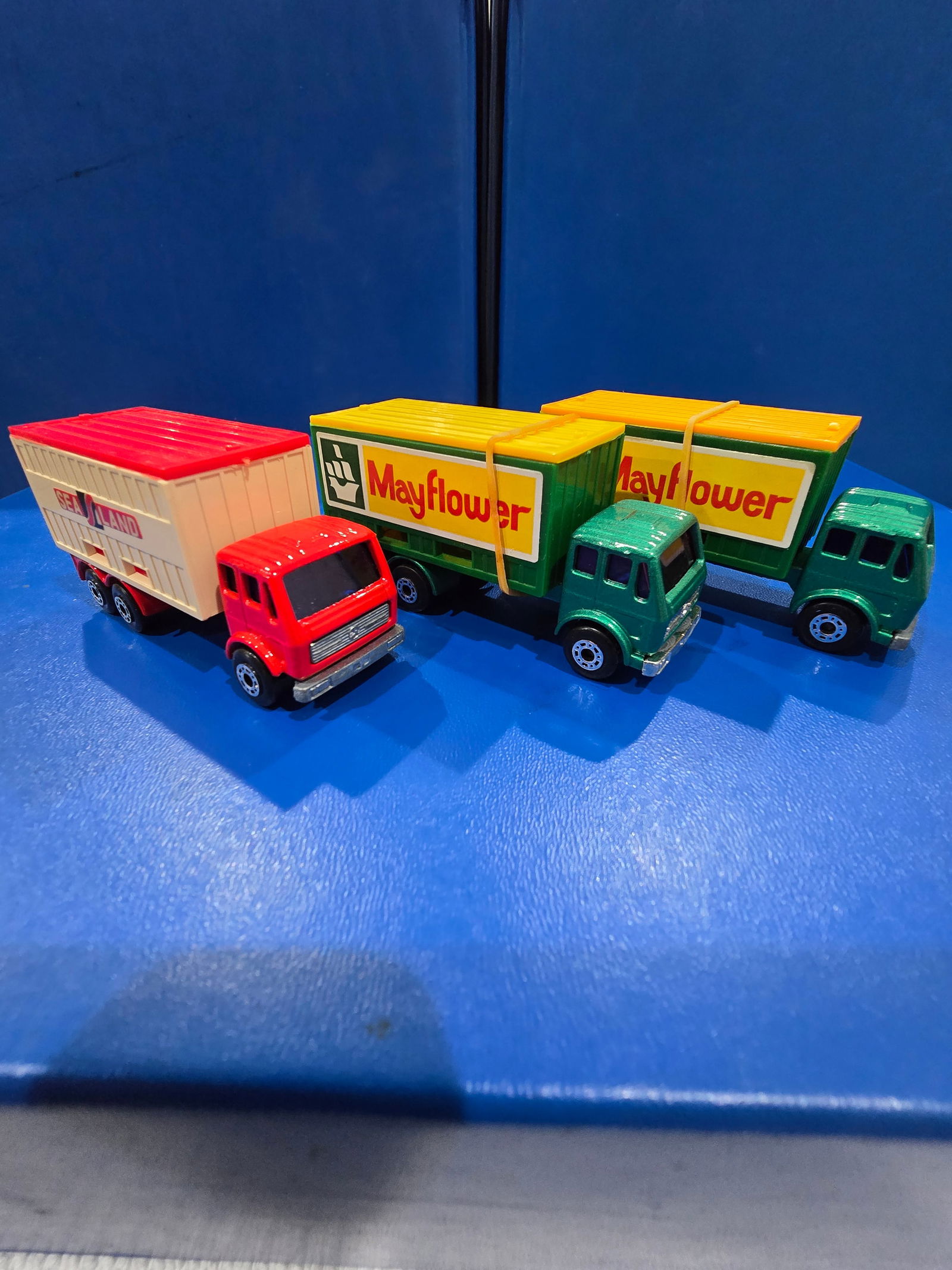 two Mayflower, green body, one purple glass, other blue glass w/ dark yellow container top, one Sea: Title: Matchbox Superfast Mercedes Container TruckDescription: two Mayflower, green body, one purple glass, other blue glass w/ dark yellow container top, one Sea and Land, red body, blue glass Date/P