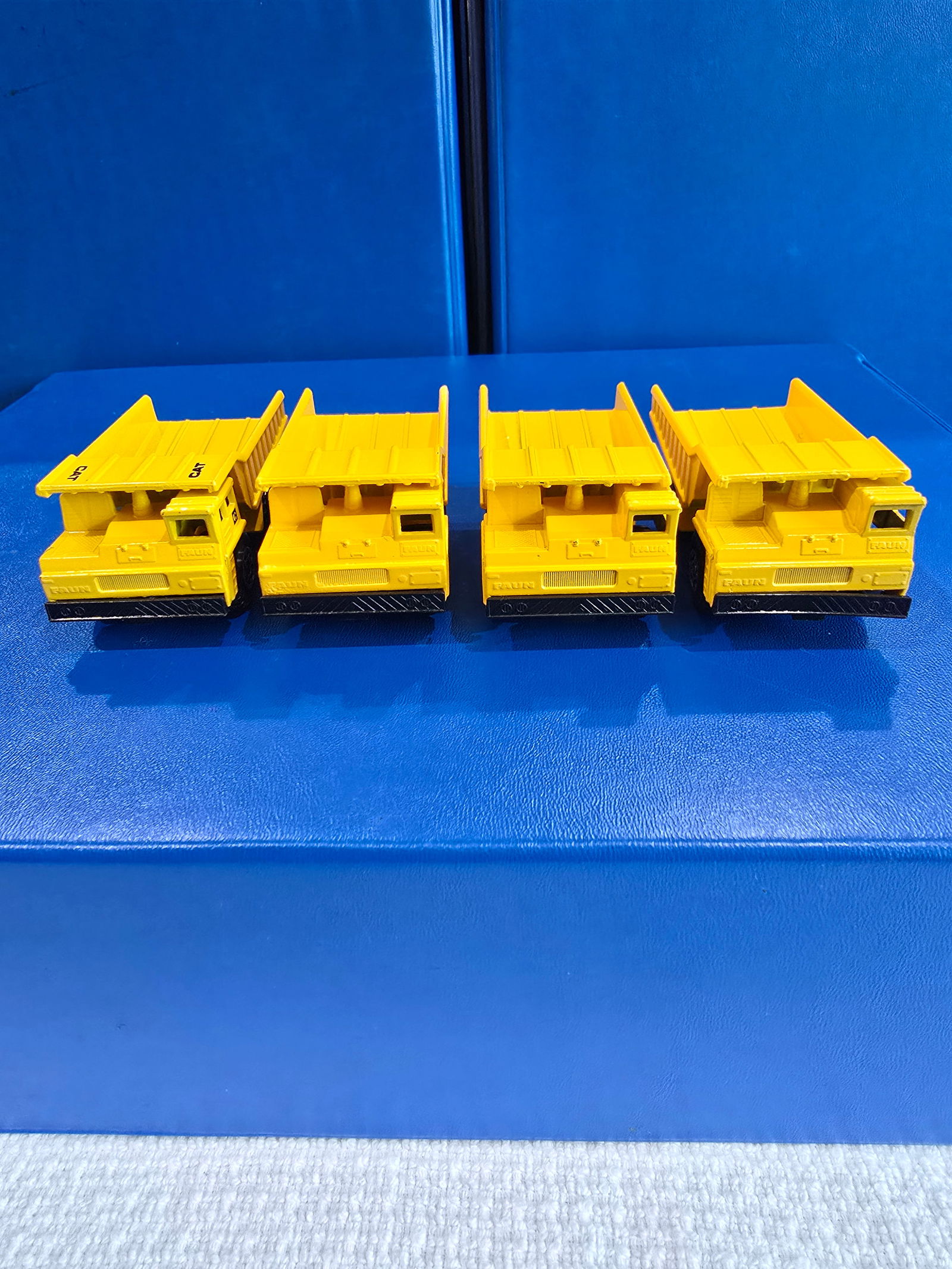 4 dump trucks, England base, black plastic base, yellow, one varation with CAT lable (1 of 4)