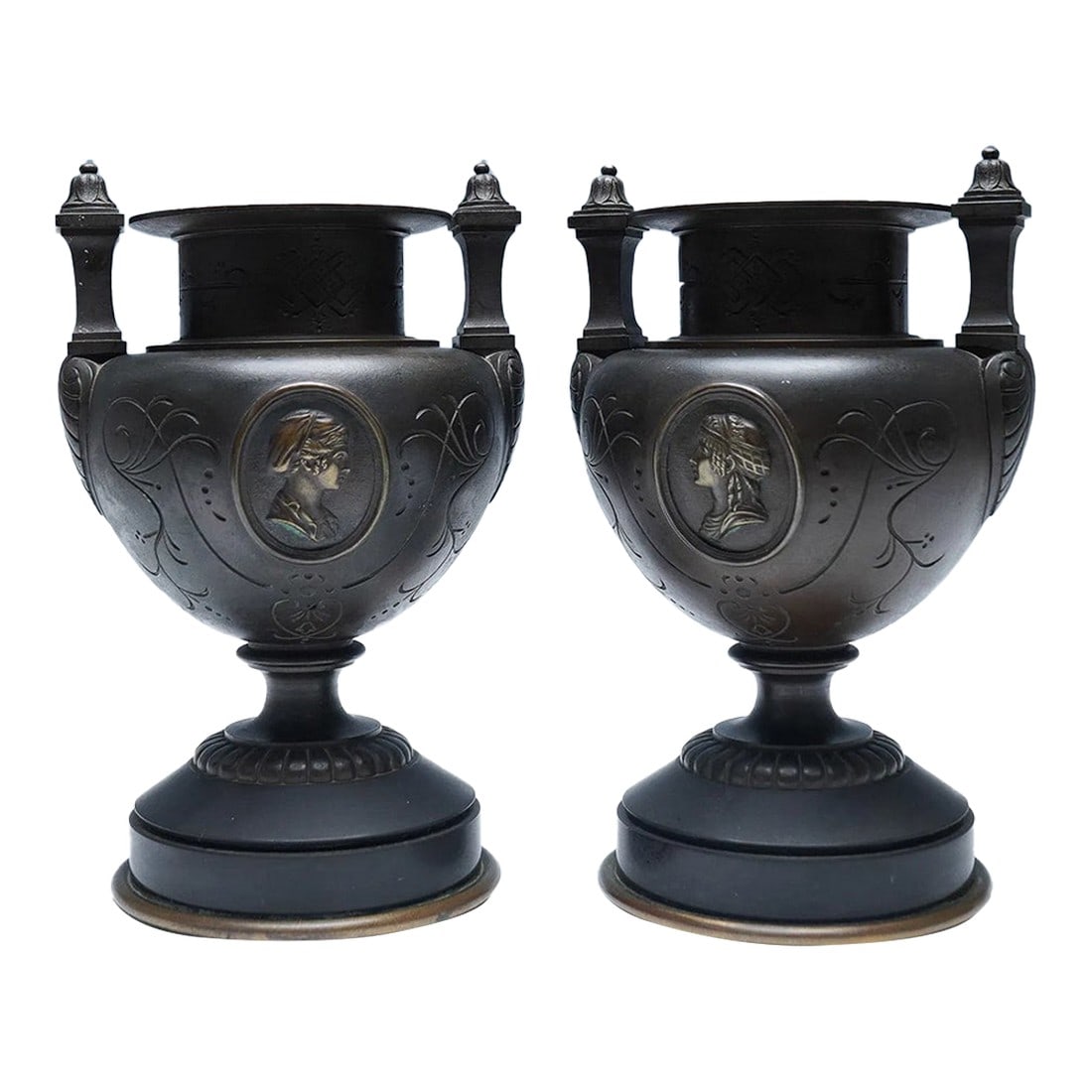 Pair of 19th-Century Patinated Bronze Urns With Neoclassical Medallions: This elegant pair of 19th-century patinated bronze urns captures the refined taste of the Neoclassical era, echoing the sophistication of Grand Tour objets d'art. Each urn features finely cast relief