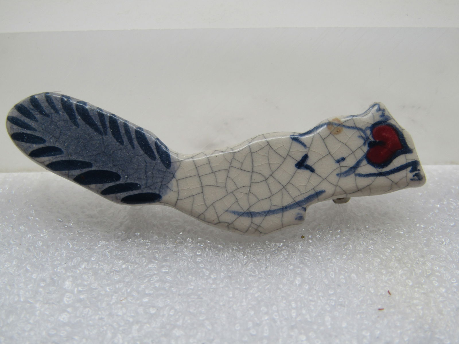 Blue & White Stoneware Squirrel Brooch, Hand Made, 1970's-1980's: Blue & White Stoneware Squirrel Brooch, Hand Made, Marekd 1 of 80 possibly and marked USA. It is a squirrel with a red heart in its mouth and done in a white crackle finish on the body and blue on the