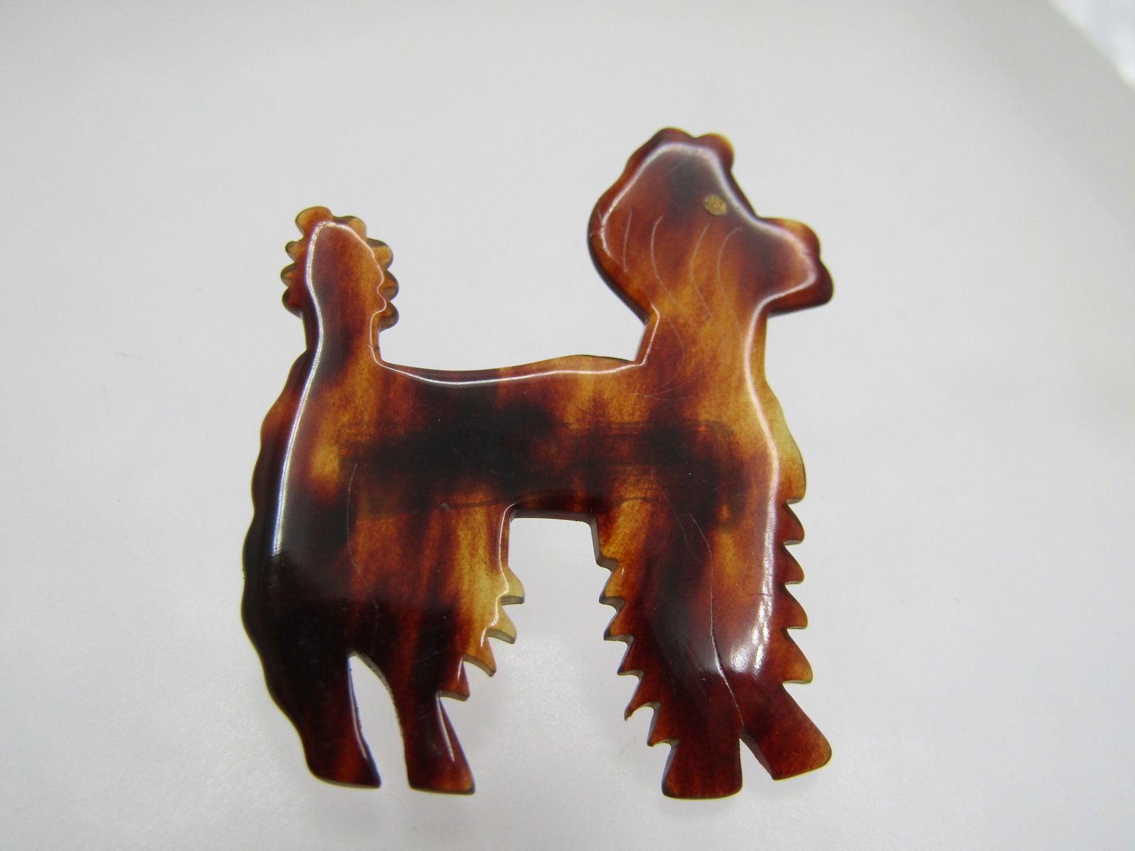 Vintage Tortoiseshell Poodle Brooch, 1960's-1970's: Vintage Tortoiseshell Poodle/Dog Brooch, 1960's-1970's. It is appx. 1-1/8" tall and wide with subtle etched markings and a brass eye and little pom pom designs on the tail and les. It is not signed or