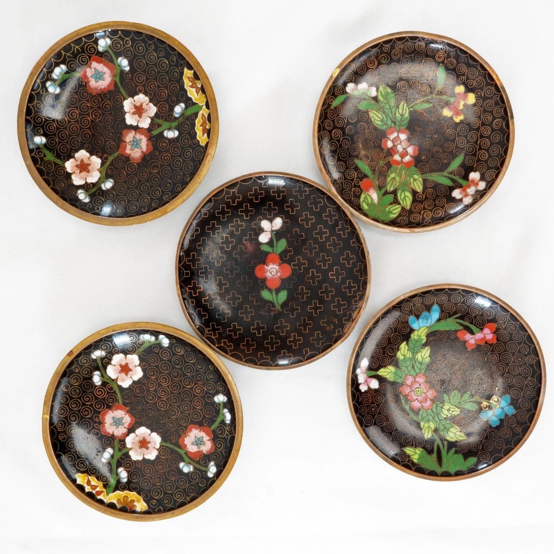 5 1930s Chinese Floral Cloisonne Coasters: Title:5 1930s Chinese Floral Cloisonne Coasters Size:Each coaster – 3 ¾ in (9.5 cm) diameter x 9/16 in (1.4 cm) deep. Description:A set of 5 small handmade Chinese dishes that have been dec