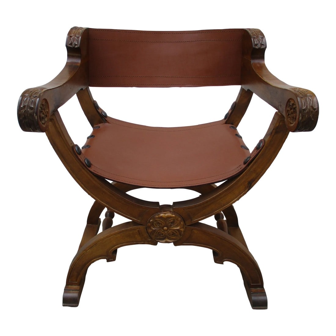 Savonarola Style Wood and Leather Chair: A classic Savonarola style leather and carved wooden chair. This piece has the look, but was not designed to completely fold inward as many of these chairs do. The leather is pined in place by large r