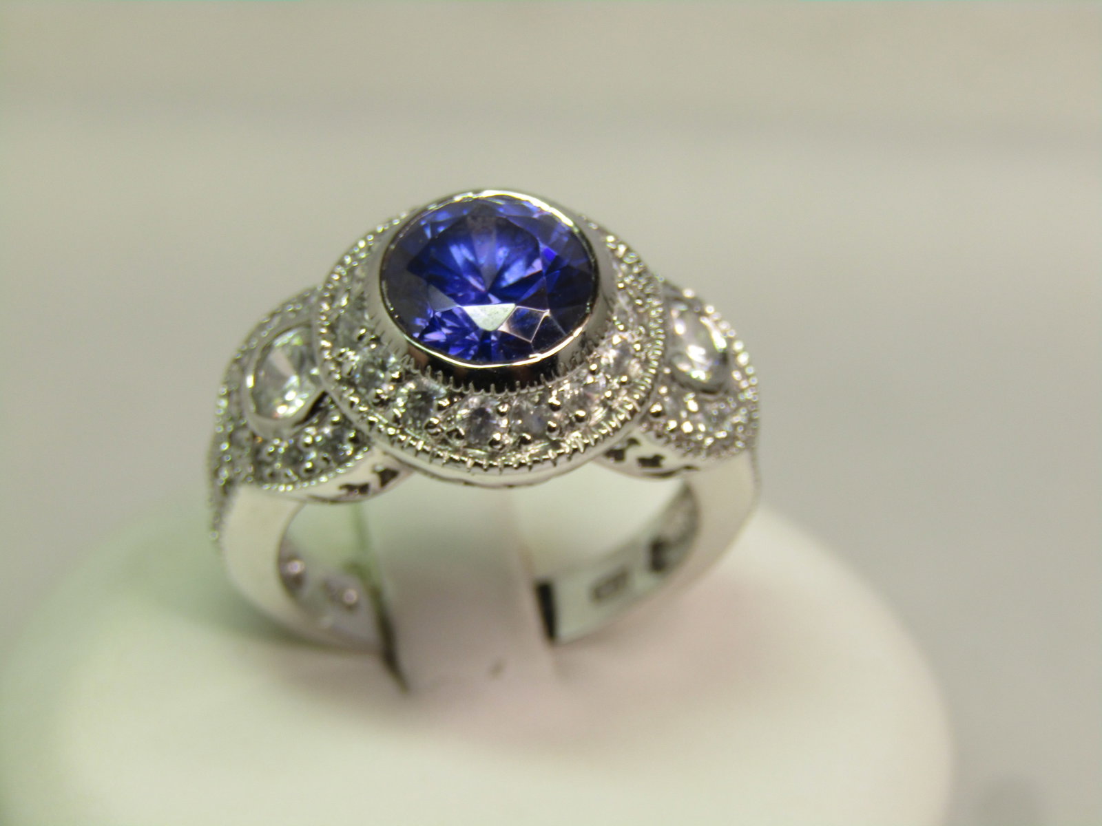 Blue & Clear CZ Ring, Sz. 7, Marked .925 and Signed ADL, 1990's: Blue & Clear CZ Ring, Sz. 7, Marked .925 and Signed ADL, 1990's. The stones are testing as cz and not glass. It has an 8mm round sapphire blue colored stone on t op with a circle of clear stones an an