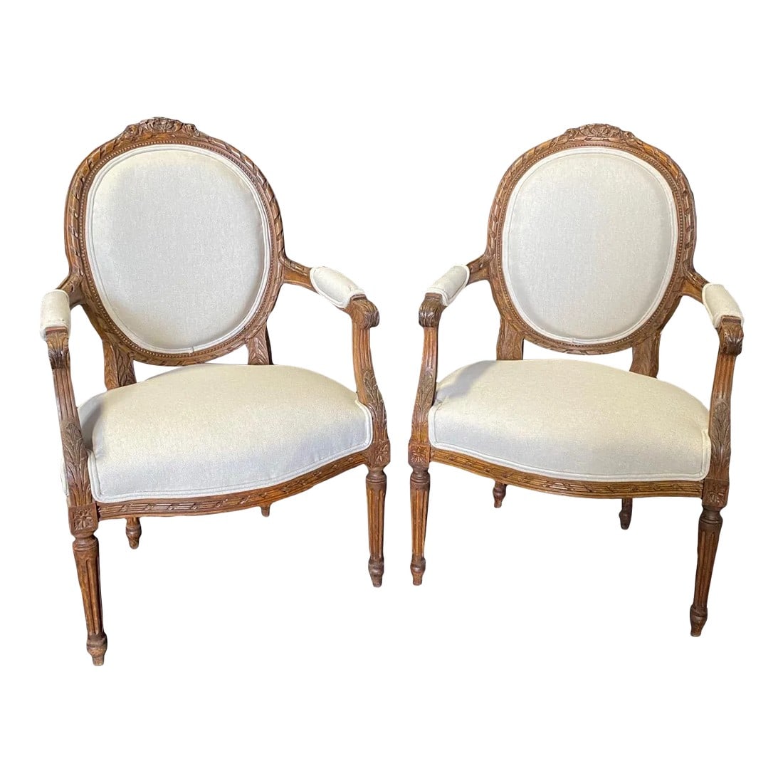 Classic French Antique Highly Carved Louis XVI Armchairs or Fauteuils -A Pair: Pair of antique 19th century French Louis XVI armchairs with new neutral high end British upholstery. Carved beautifully in walnut with a fantastic patina. Each chair is raised by fine and uniquely sh