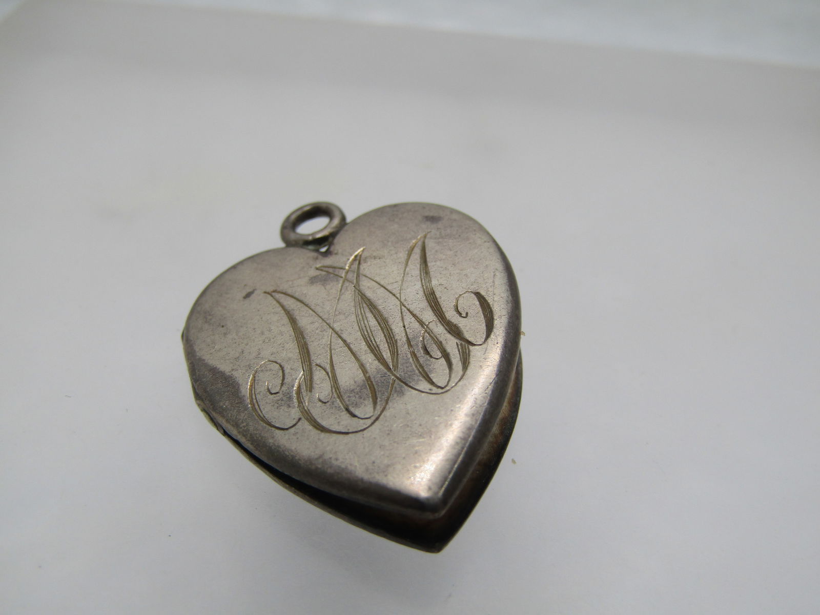Vintage Sterling Early 1900's Heart Locket Engraved MM: Title: Vintage Sterling Early 1900's Heart Locket Engraved MM Description: Vintage Sterling Early 1900's Heart Locket Engraved MM. Inside the heart one ach side is scratched XII perhaps dating it to 1
