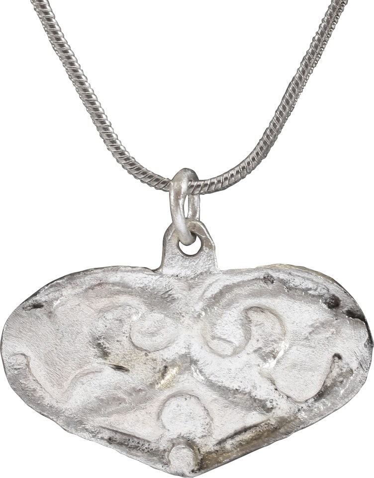 VIKING HEART PENDANT NECKLACE, C.900-1050 AD: Just over 1" width, and with deep relief incised decoration. Heart form with central inscribed trefoil of abstracted and abbreviated form with the rounded edges scrolling and ending in leaves The form