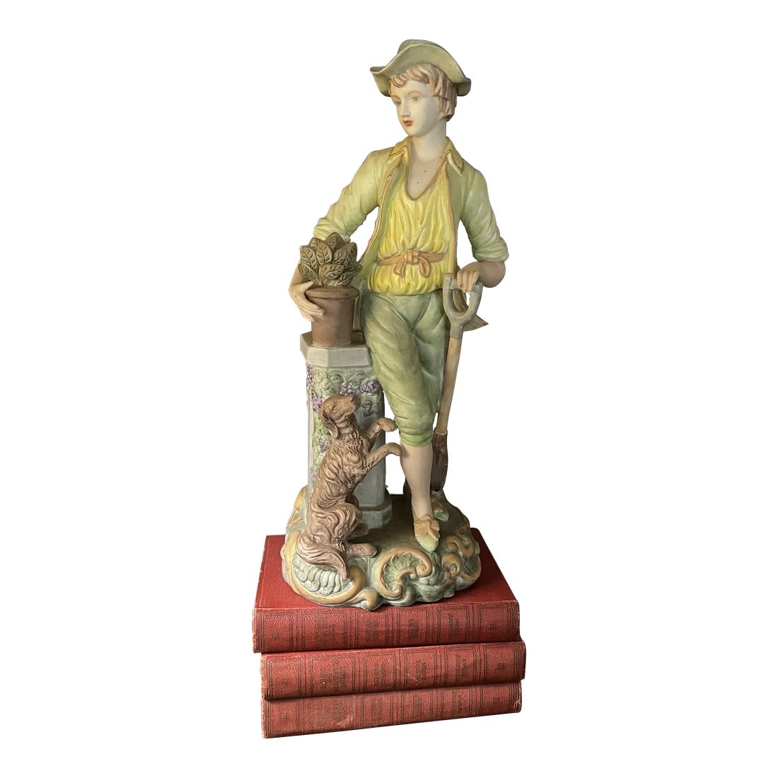 Vintage Porcelain Statue of Boy and Dog a Tall Piece: This hand painted bisque boy figurine / statue is precious and beautifully detailed. He is holding a shovel with its tip resting on the ground, a potted plant in his opposite hand and a begging puppy