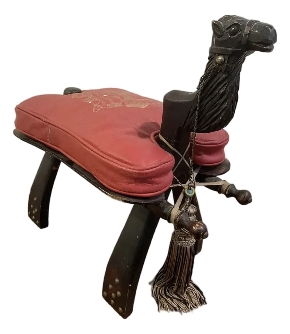 Mid 20th Century Vintage Turkish Camel Saddle Stool in Red Leather: This Mid 20th Century Vintage Turkish Camel Saddle Stool in Red Leather is sure to be the conversation piece of the evening! Condition: Alterations: Original Condition Unaltered Imperfections: Some Im