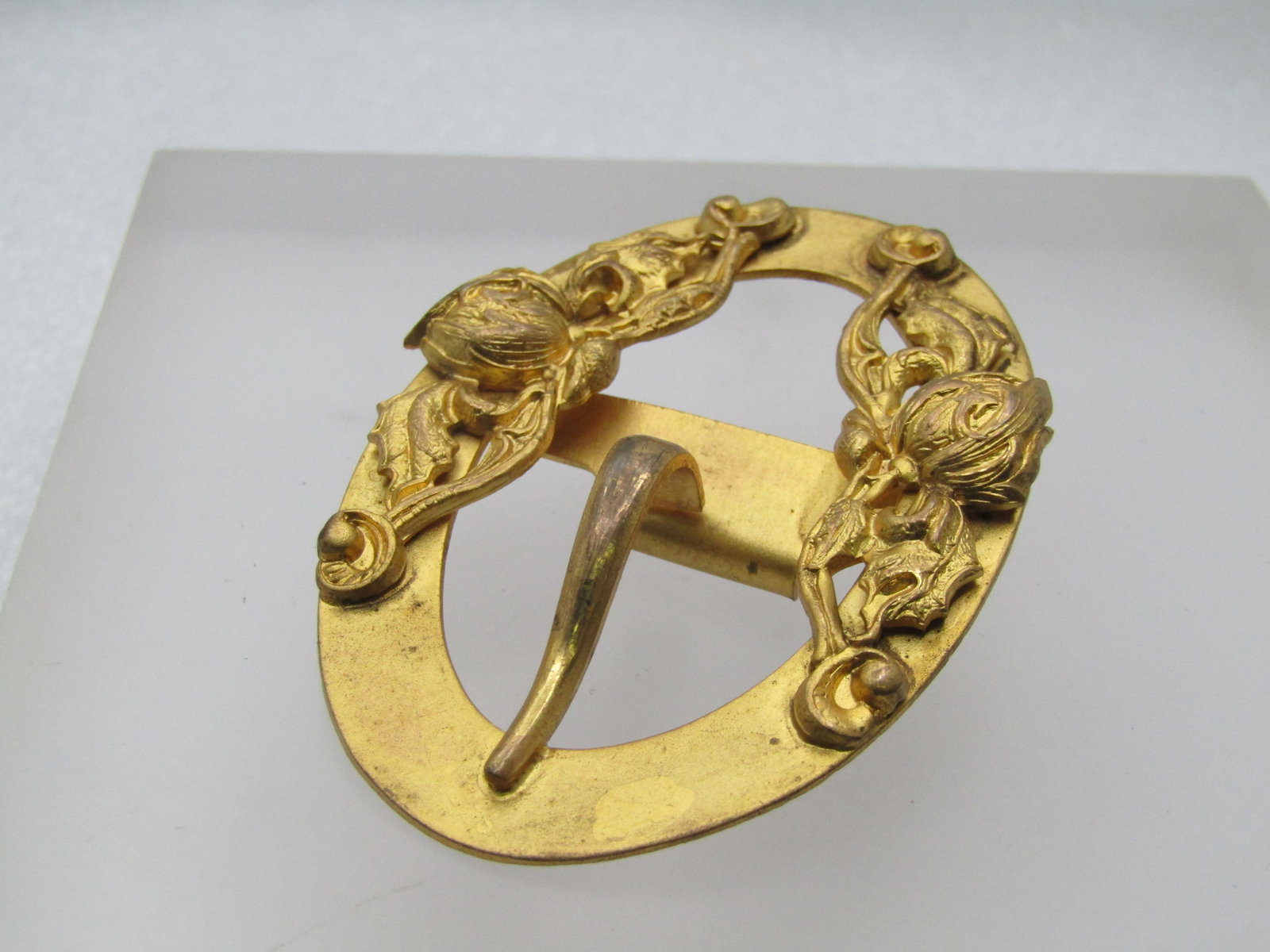 Vintage Victorian Themed Buckle, Floral: Vintage Victorian Themed Buckle, Floral. Gold tone and 2.5" wide and 1.5" tall - oval with a floral repousse design on top and bottom. It has a faux hook with the tab on the bottom and a whole on the 