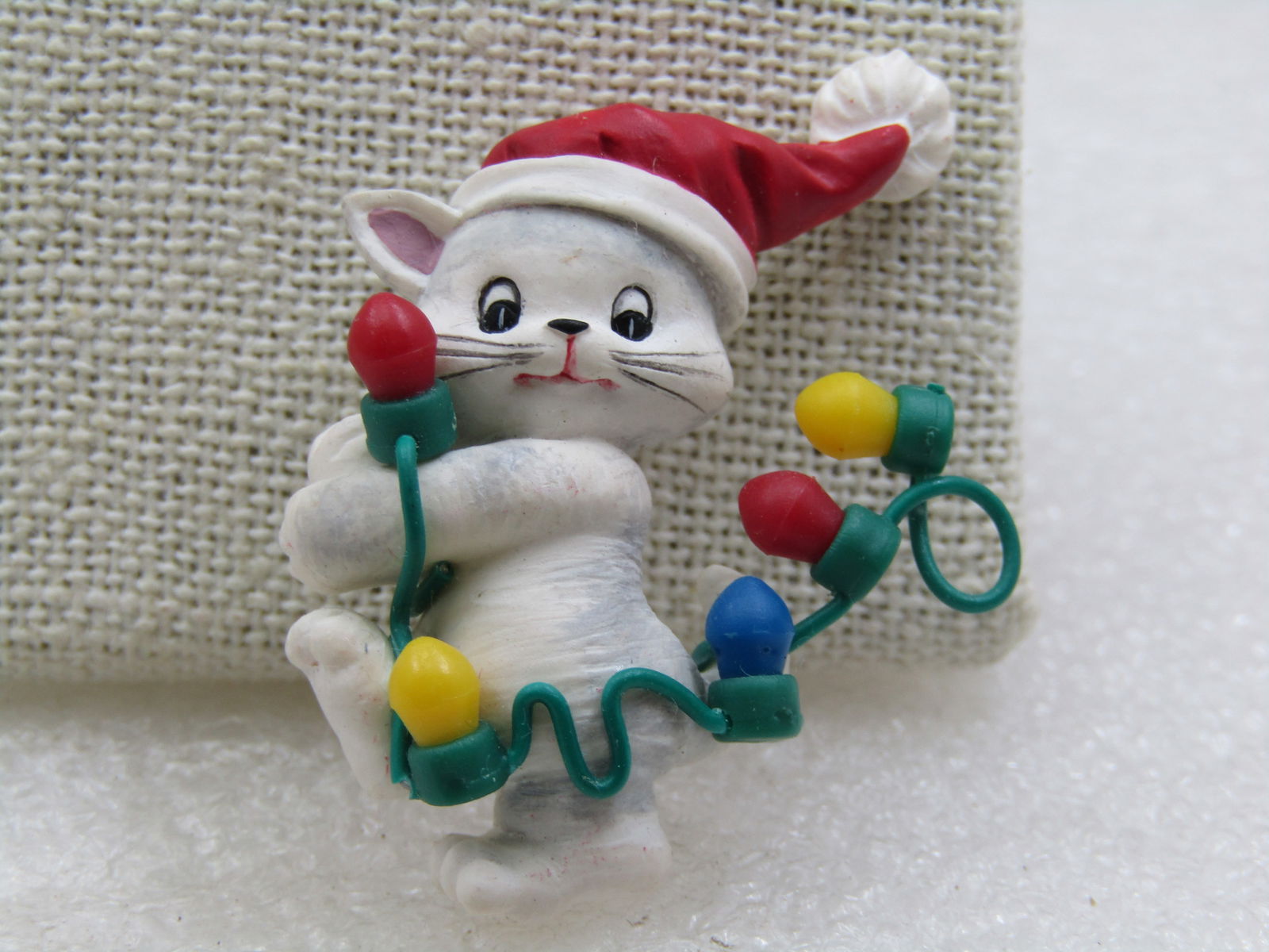 Vintage Resin Christmas Cat with Lights & Santa Cap: Vintage Resin Christmas Cat with Lights & Santa Cap. It is appx. 1.5" tall and 1.25" wide. White and gray tabby cat hugging a string of Christmas lights trailing behind with his red and white Santa Ca