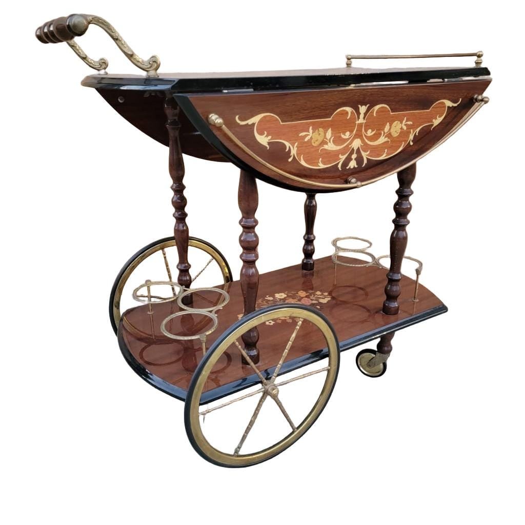 Vintage Italian Marquetry Two Tier Drop-Leaf Dessert/Bar Cart Trolley: Materials: metal, wood Vintage Italian Marquetry Two Tier Drop-Leaf Dessert/Bar Cart Trolley Impress your guests with this spectacular Hollywood Regency serving cart. Italian marquetry inlaid design w