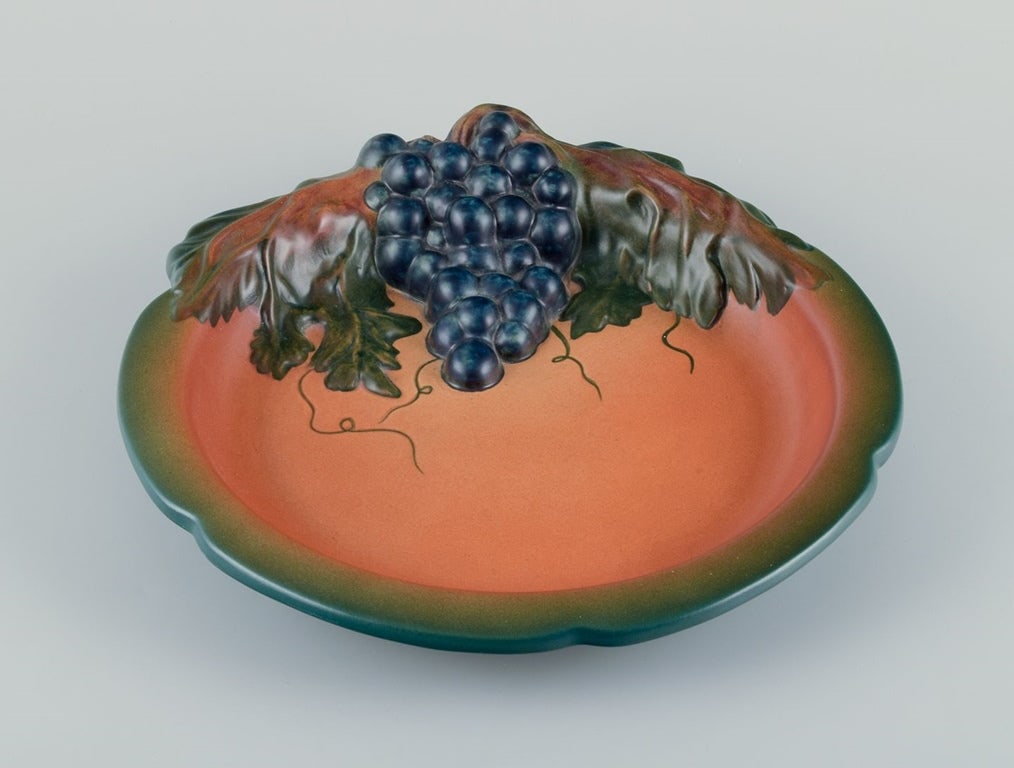 Erik Magnussen for Ipsens, Denmark. Art Nouveau dish in ceramic with vines and foliage. 1920s.: Erik Magnussen for Ipsens, Denmark. Art Nouveau dish in hand-painted ceramic, modelled with vines and foliage. Model number 135. From the 1920s. In perfect condition. Stamped. Dimensions: Diameter 31.