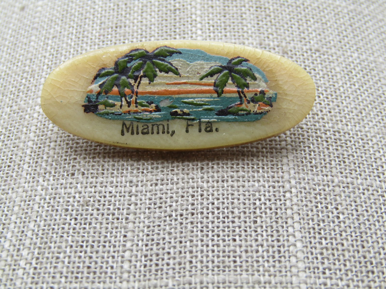 Vintage Painted Miami , Florida Brooch, Souvenir , 1940's-1950's: Vintage Painted Miami , Florida Brooch, Souvenir , 1940's-1950's. Oval 1.75" wide and .75" tall. It is on a lacquered either mother-of-pearl or heavy plastic base. it is hard to tell due to the lacque