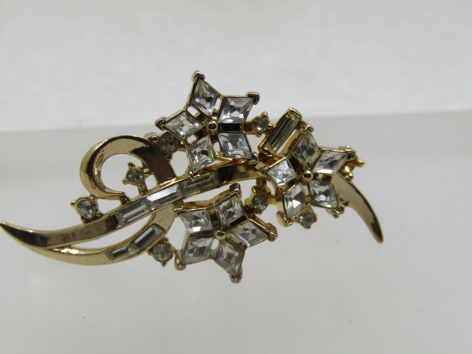 Vintage Rhinestone Floral Stem Brooch, Crown Trifari , 1940's-1950's: Vintage Rhinestone Floral Stem Brooch, Crown Trifari , 1940's-1950's. Signed with a crown of the T in Trifari and marked Pat. Pend. This is a gold tone brooch with a slight dome in the center and gold