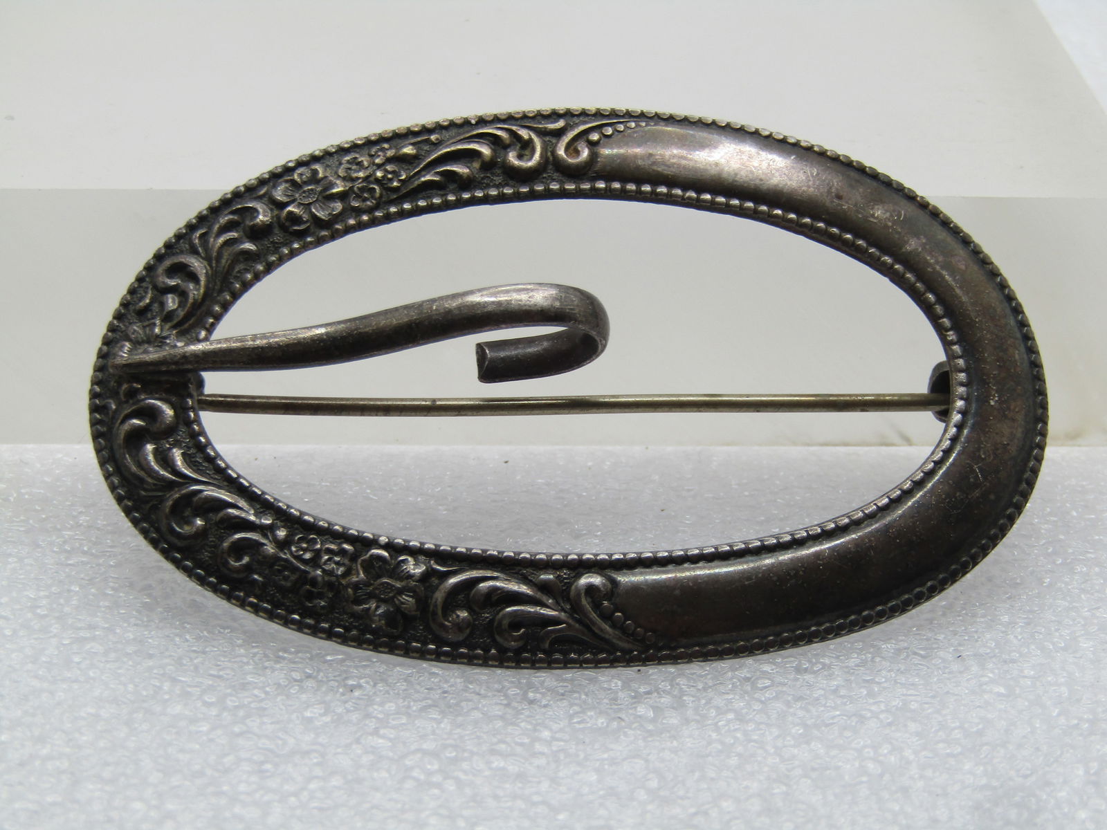 Antique Sterling Brooch/Sash Buckle, C-Clasp, Victorian to 1920's: Antique Sterling Brooch/Sash Buckle, C-Clasp, Victorian to 1920's. Large oval with a raised scrolled and floral design on the buckle end of the brooch/buckle. It is appx. 2-7/8" wide and 1.75" tall an