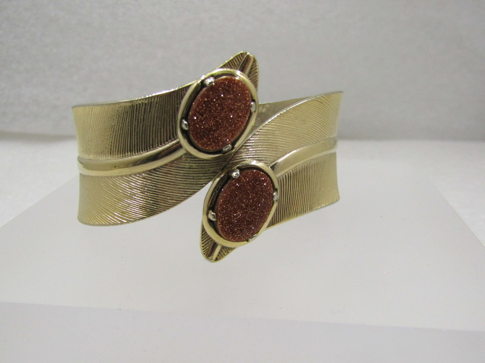 Vintage Hinged Cuff Goldstone Bracelet, 6.75", 1960's-1970's: Vintage Hinged Cuff Goldstone Bracelet, 6.75", 1960's-1970's. This has a textured leaf-like design with a raised vein down the center. It comes to an angled point at the top center where it opens to s