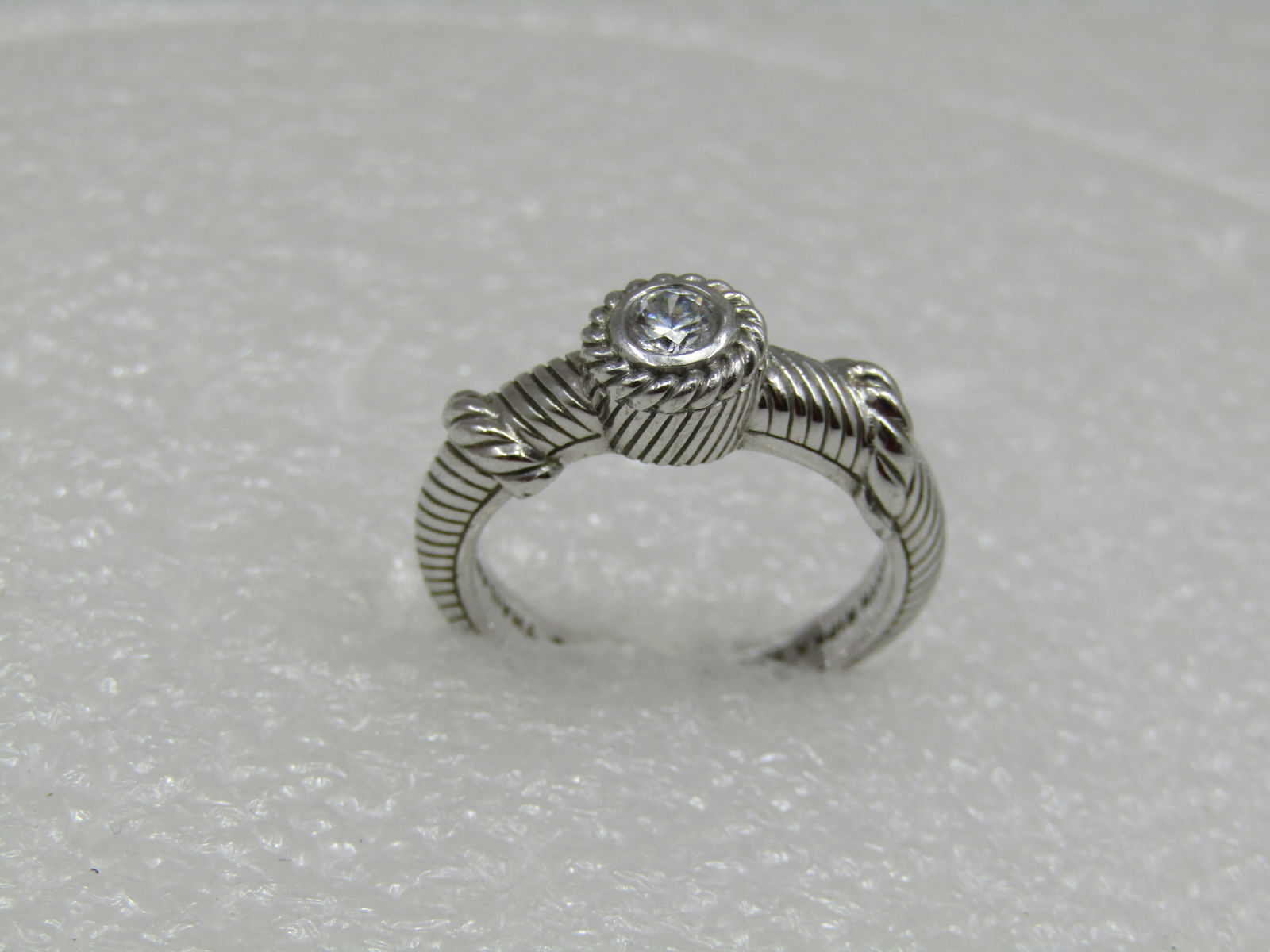 Sterling Contemporary Judith Ripka CZ Ring, Sz. 8, Cable/Rope Accents: Sterling Judith Ripka CZ Ring, Sz. 8, Cable/Rope Accents. Signed Judith Ripka, Thailand, CZ and .925 and tested. Weight is appx.4.63 gr. 4.5mm bezel-set CZ. The ring is appx. 7.3mm at top center and t