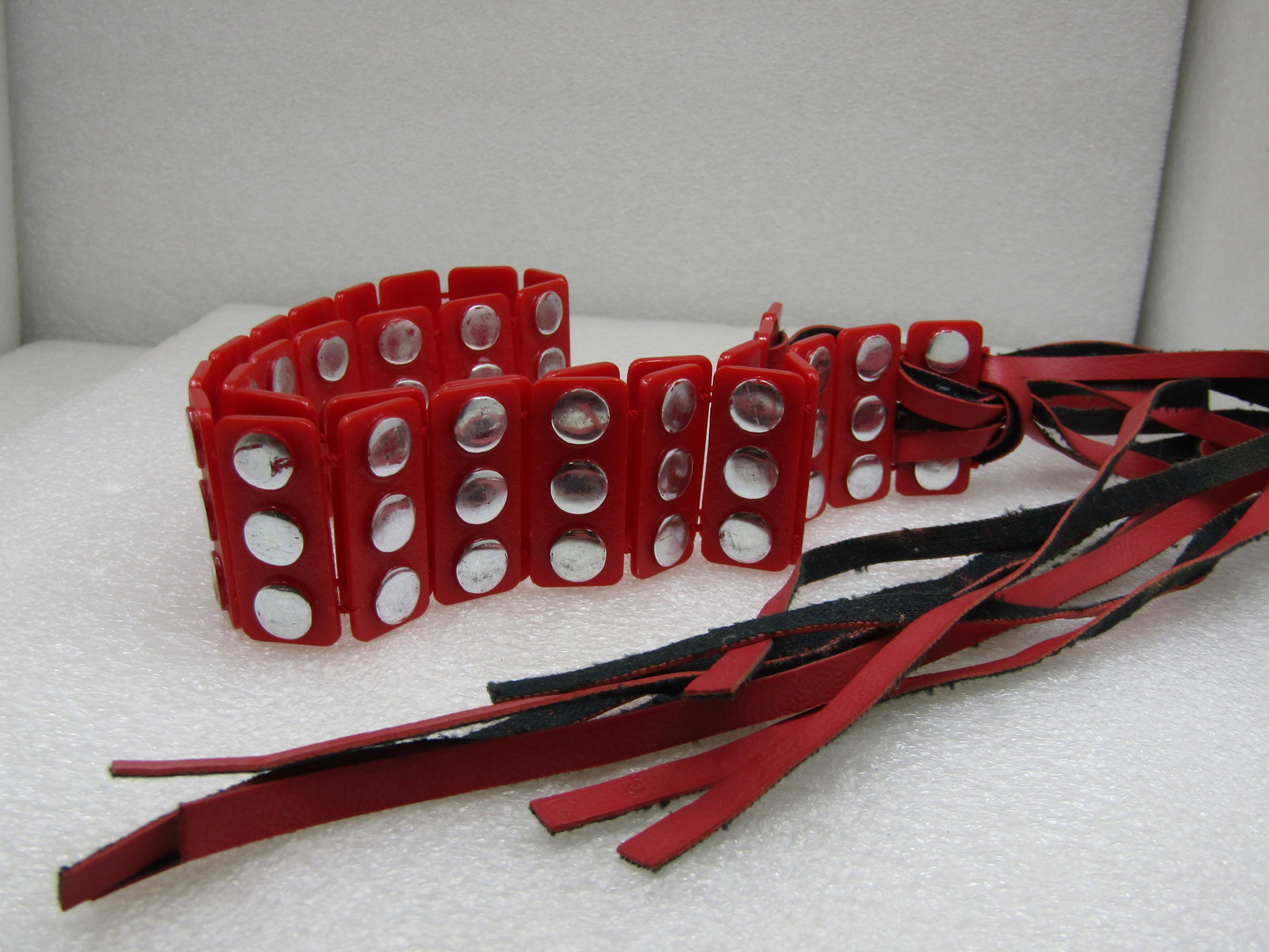 Vintage Red Plastic Silver Studded Belt, Tassels, 1970's-1980's: Vintage Red Plastic Silver Studded Belt, Tassels, 1970's-1980's, 1.5" wide. Articulated with movement between each link that has three silver 1/3" silvertone round studs. The red plastic main part of