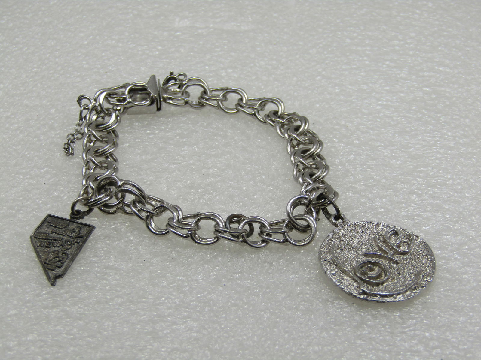 Vintage Sterling Silver Charm Bracelet, 7", Signed TC: Vintage Sterling Silver Charm Bracelet, 7", Signed TC with Love, Nevada Charms. Double link, 9.5mm wide, tested, weight of 20.79 gr. Age is appx. 1960's-1970's. The Love charm could e a pendant, it ha