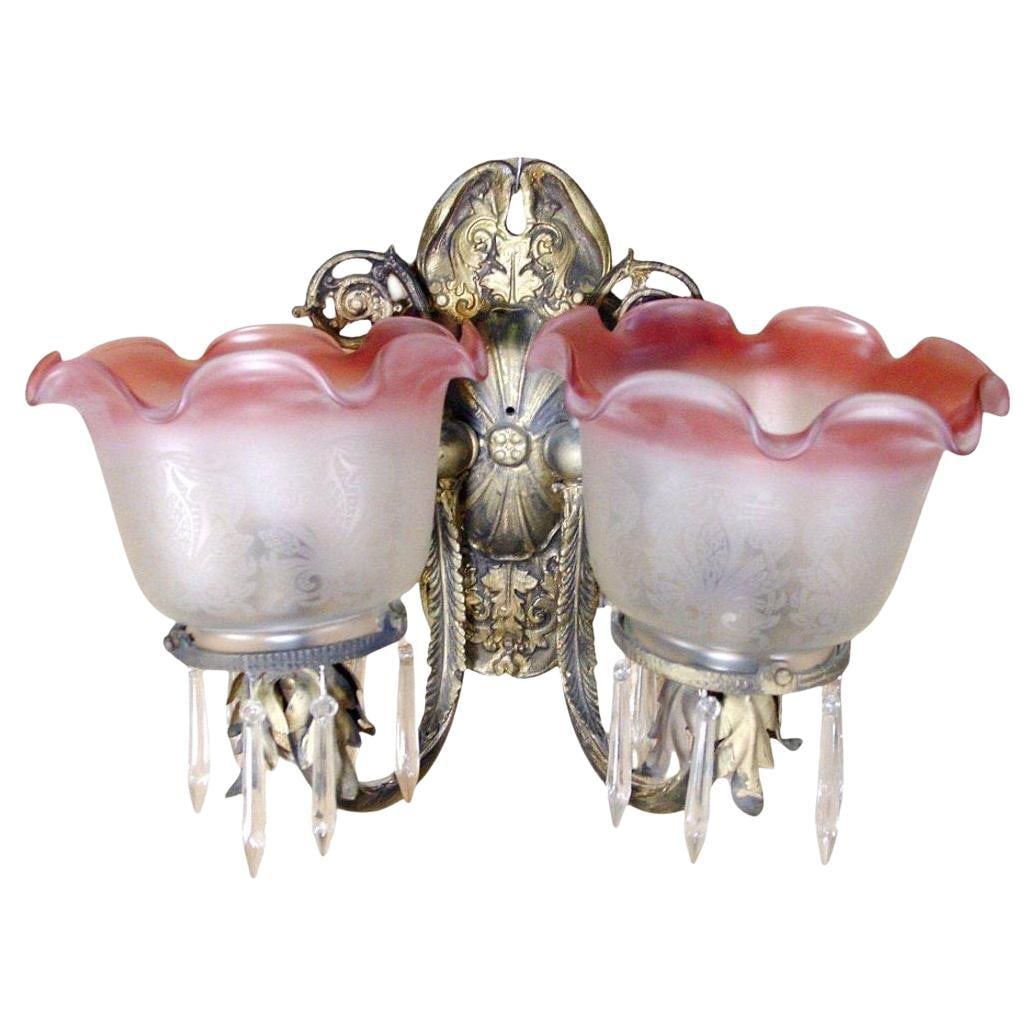 Neoclassical Brass Sconce With Acid Etched Rose Shades: Title: Neoclassical Brass Sconce With Acid Etched Rose Shades Description: Neoclassical wall sconce featuring a pair of feathered brass arms extending from a floral motif wall mount. The floral motif