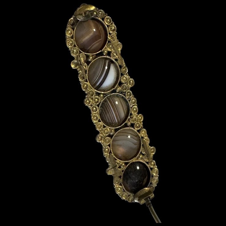Antique Victorian Banded Agate Antique Brooch: This elegant brooch was created in the mid to late 1800s. This brooch is constructed from gilded metal or Pinchbeck formed into a design resembling cannetille work. The brooch is detailed with 5 Agate
