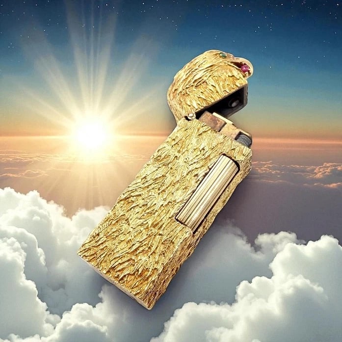 Vintage Dunhill 18k Yellow Gold Ruby Emerald Eagle Rollagas Lighter 1950's: This 1950s vintage Dunhill Rollagas lighter is crafted in solid 18k yellow gold, intricately textured to resemble an eagle’s feathers. The eagle’s head features vivid emerald eyes and a ru