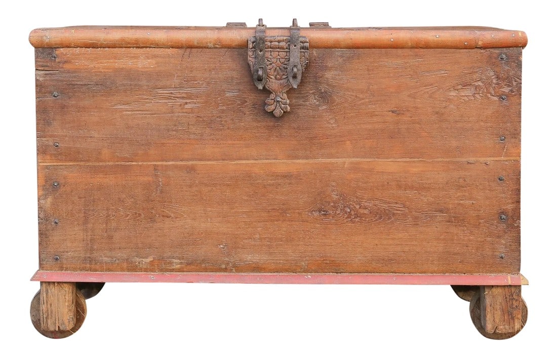 Antique Indian Teak Wedding Trunk: Originally a Dowry chest made from teak wood, stands on wooden caster legs, iron side handles and nail head details, it has a red trim molding and its center top door opens with a secret compartment.