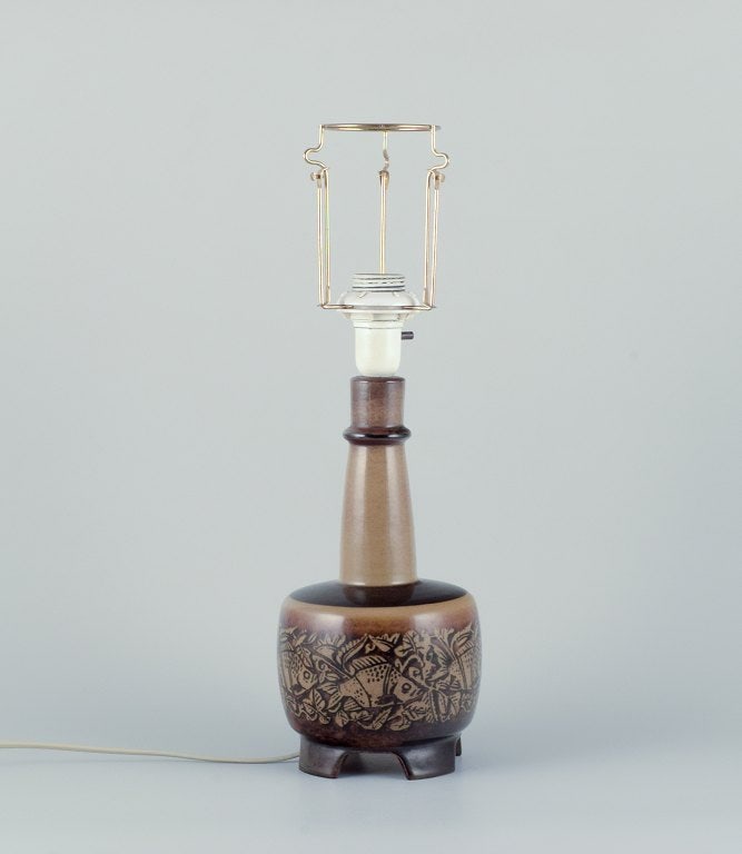 Nils Thorsson for Royal Copenhagen. Table lamp in stoneware with a motif of swimming fish. Glaze in: Title: Nils Thorsson for Royal Copenhagen. Table lamp in stoneware with a motif of swimming fish. Glaze in brown tones. Description: Nils Thorsson for Royal Copenhagen. Table lamp in stoneware with a
