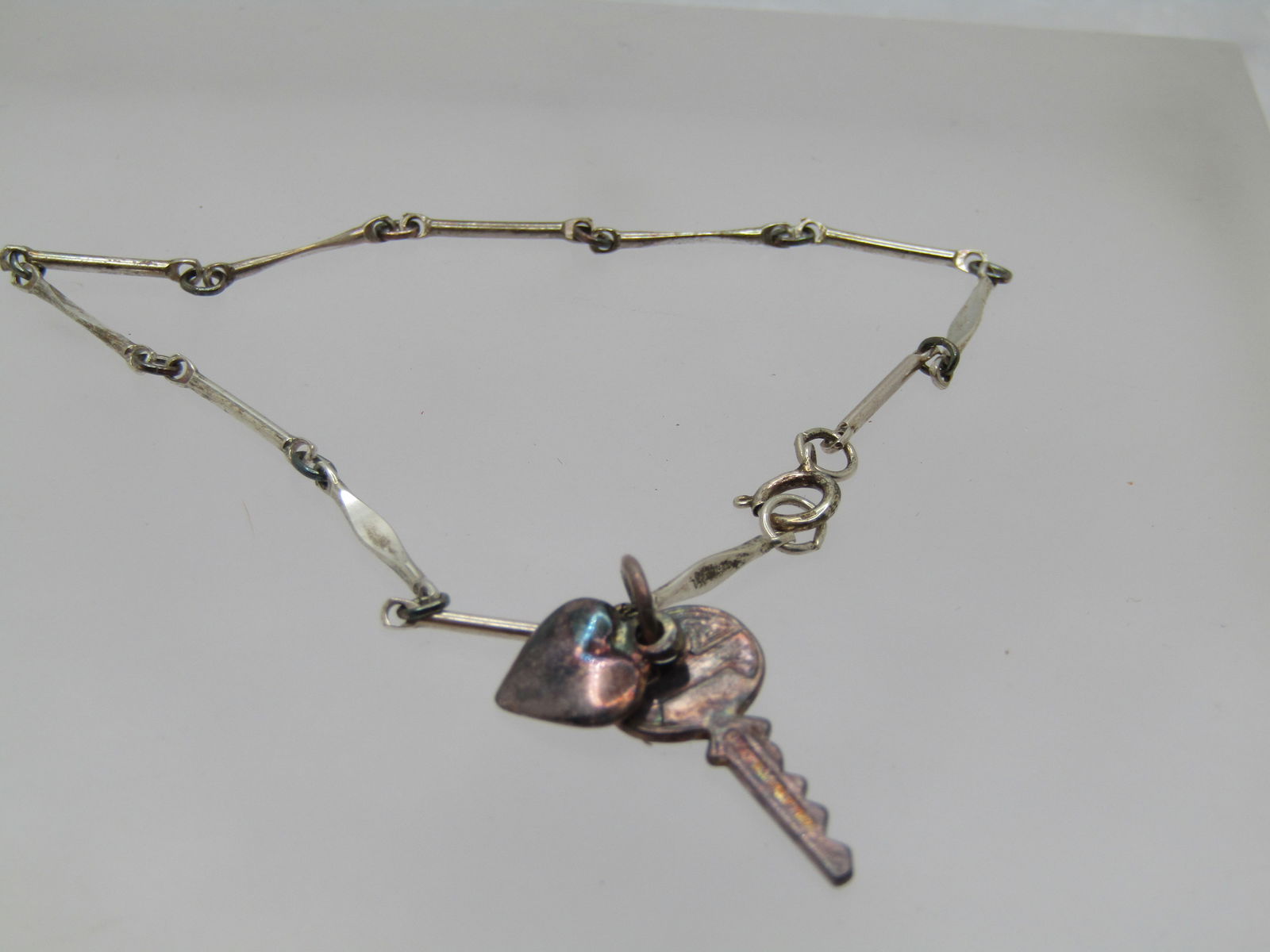 Vintage Sterling Heart Key Bracelet, Bob Siemon Designs, 7": Vintage Sterling Heart Key Bracelet, Bob Siemon Designs, 7". This has a heart charm and key charm attached to a flat tapered bar link bracelet. It is marked .925 on the spring clasp and tested. Weight